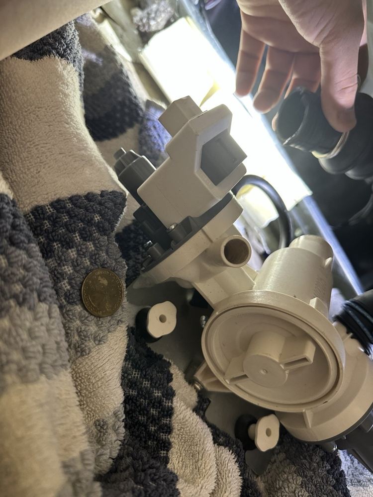 Appliance pump on a towel during inspection, a coin beside it